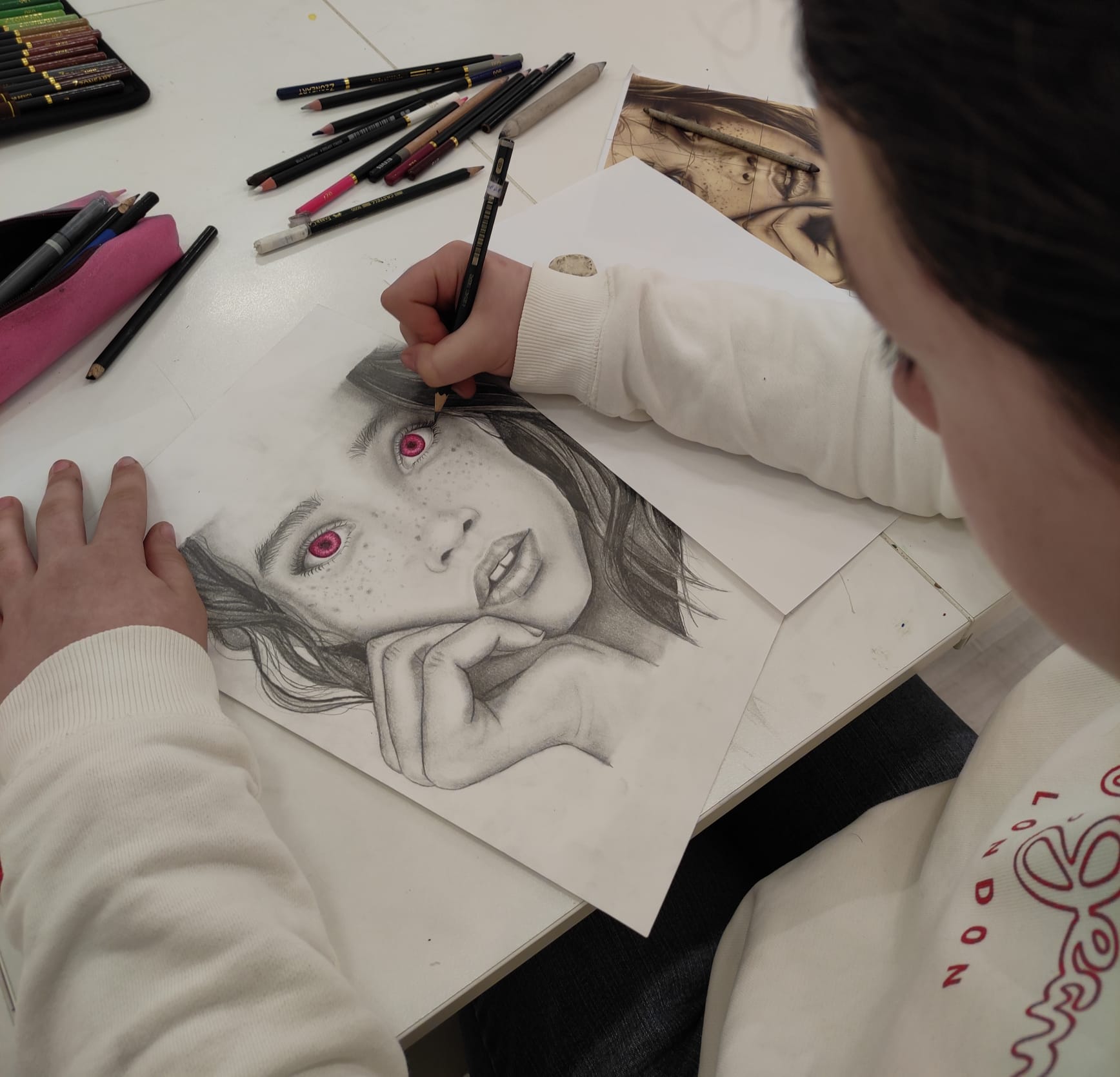 niña dibujando un rostro a lapiz con ojos rosas