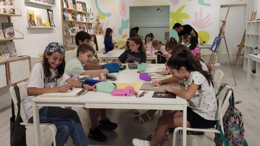 niños de mas de 12 años pintando sobre mesas blancas sentados en sillas