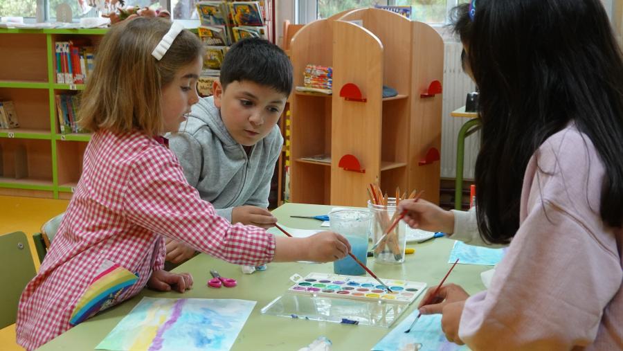 Niños en una mesa de cole, pintando y dibujando