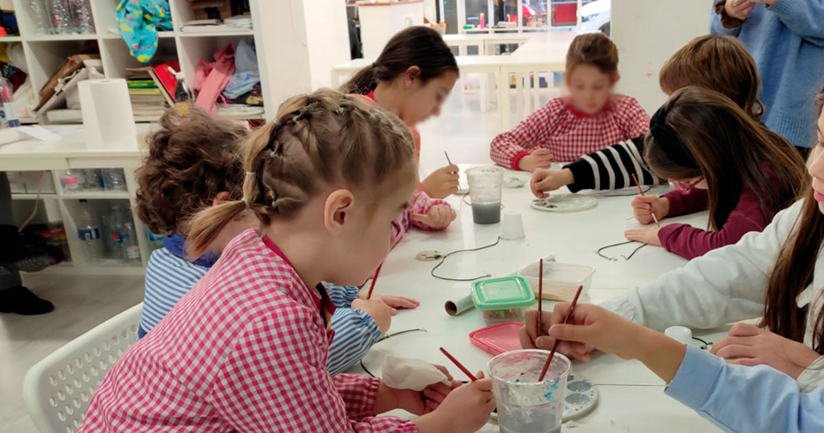 Niños dibujando con pinceles dentro del aula